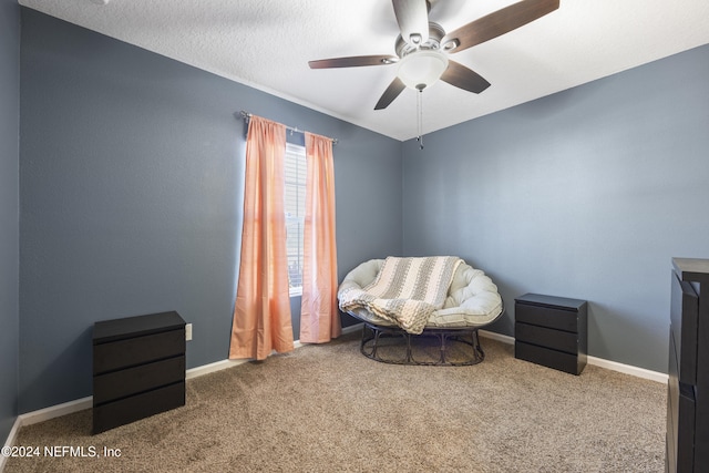 sitting room featuring ceiling fan, carpet floors, and a textured ceiling