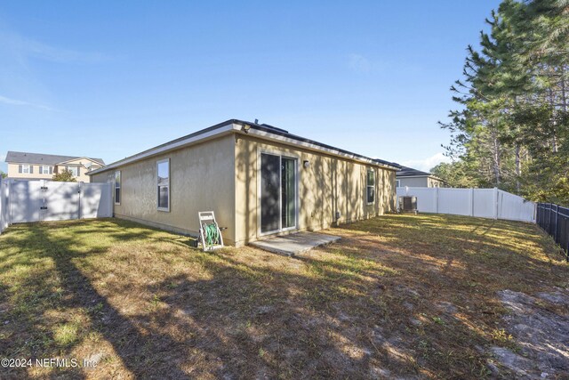 back of house featuring a lawn and central air condition unit