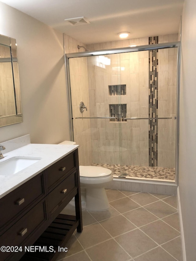 bathroom featuring vanity, tile patterned flooring, a shower with shower door, and toilet