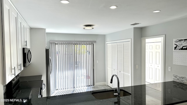 kitchen featuring range with electric stovetop, kitchen peninsula, sink, and white cabinets