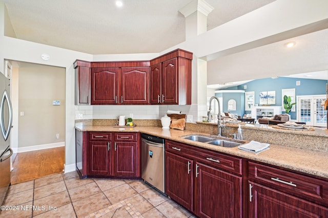 kitchen with sink, light tile patterned floors, a textured ceiling, appliances with stainless steel finishes, and light stone counters