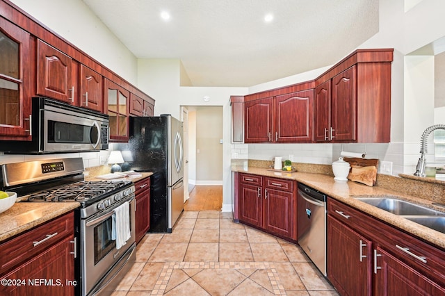 kitchen featuring sink, decorative backsplash, light tile patterned floors, light stone counters, and stainless steel appliances