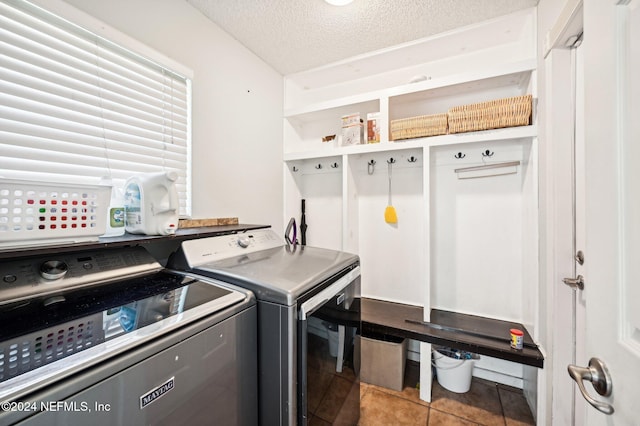 washroom featuring washer and dryer, light tile patterned floors, and a textured ceiling