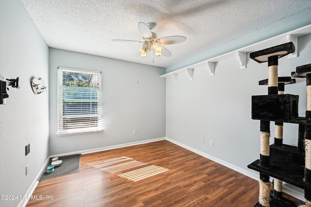 interior space featuring ceiling fan, wood-type flooring, and a textured ceiling