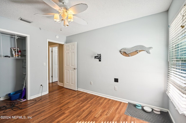 unfurnished bedroom with hardwood / wood-style flooring, ceiling fan, a textured ceiling, and a closet