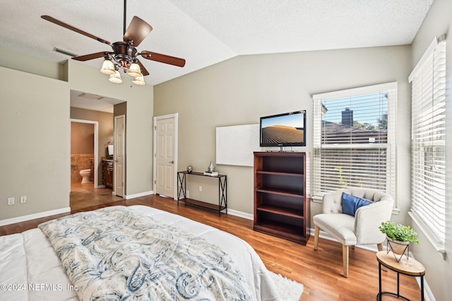 bedroom featuring ceiling fan, lofted ceiling, connected bathroom, and multiple windows