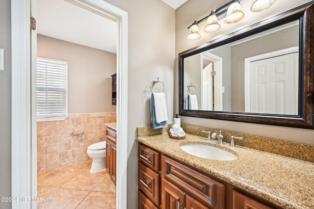 bathroom with tile patterned flooring, vanity, toilet, and tile walls