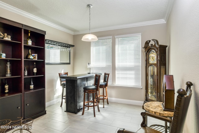 dining area with a textured ceiling, plenty of natural light, indoor bar, and ornamental molding