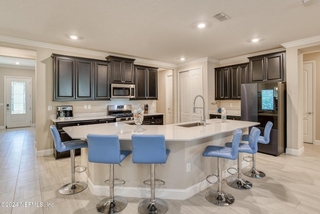 kitchen featuring a breakfast bar, a kitchen island with sink, sink, and appliances with stainless steel finishes