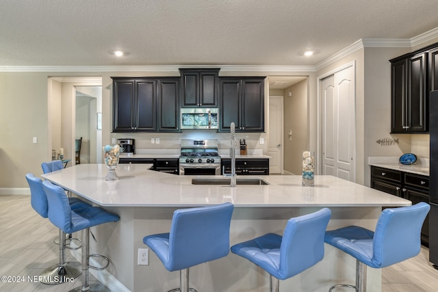 kitchen featuring a kitchen bar, appliances with stainless steel finishes, a textured ceiling, and a spacious island