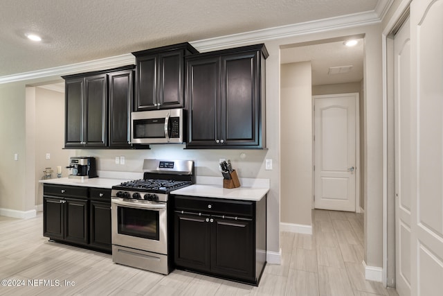 kitchen with appliances with stainless steel finishes, a textured ceiling, and ornamental molding