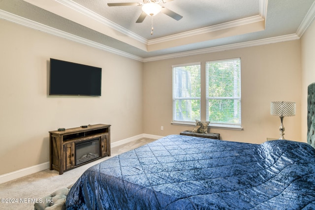 bedroom with ceiling fan, carpet floors, crown molding, and a tray ceiling