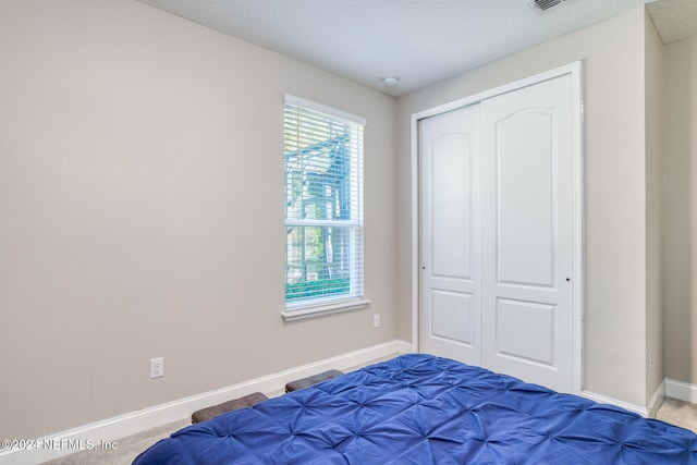 carpeted bedroom with a textured ceiling and a closet