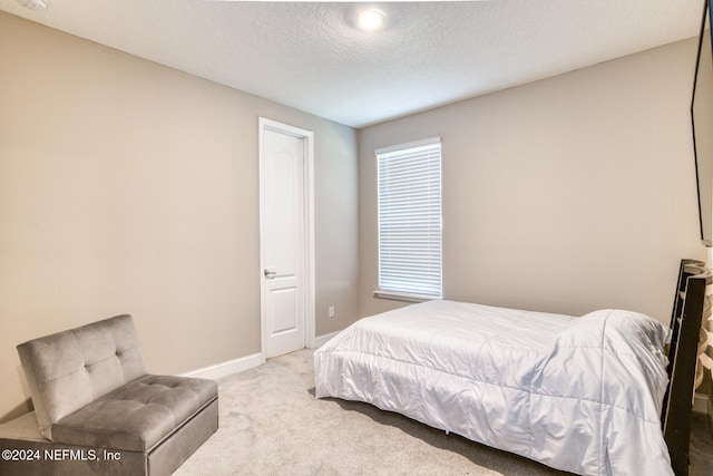 bedroom featuring light carpet and a textured ceiling