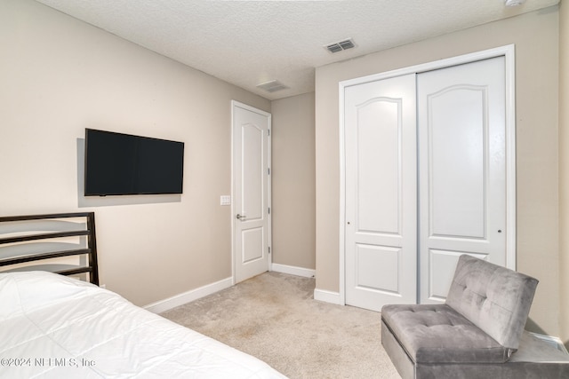 bedroom featuring a textured ceiling, light carpet, and a closet