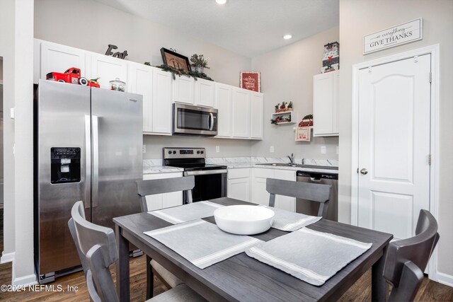 kitchen featuring stainless steel appliances, white cabinetry, and dark wood-type flooring