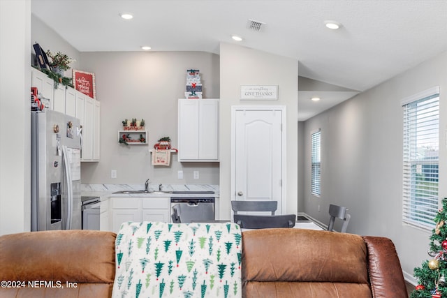 kitchen featuring stainless steel appliances, vaulted ceiling, and white cabinetry