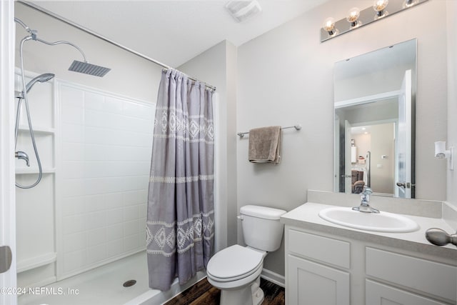 bathroom with hardwood / wood-style flooring, vanity, toilet, and walk in shower