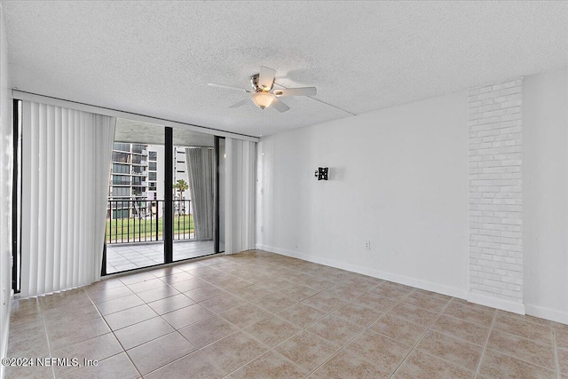 tiled empty room featuring ceiling fan and a textured ceiling