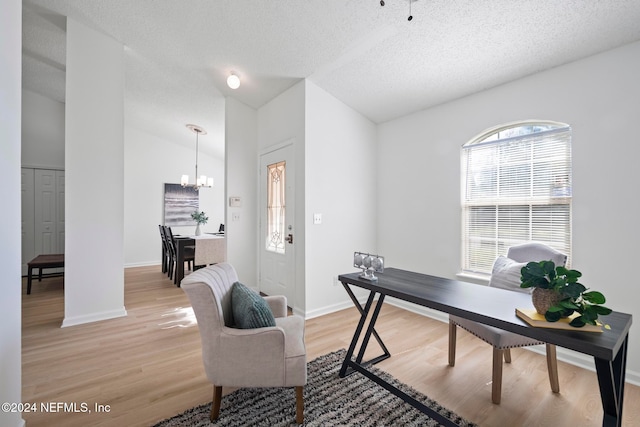 office space featuring a wealth of natural light, light hardwood / wood-style floors, lofted ceiling, and an inviting chandelier