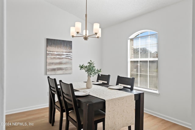 dining room featuring light wood-type flooring, a textured ceiling, and a notable chandelier