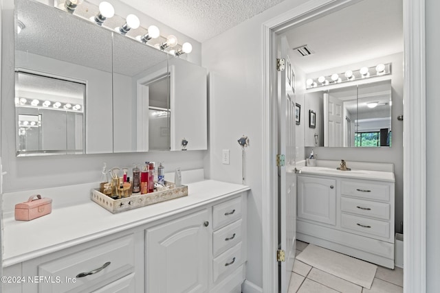 bathroom with tile patterned floors, vanity, and a textured ceiling