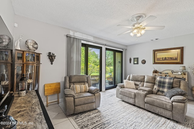 living room with ceiling fan, light tile patterned flooring, and a textured ceiling