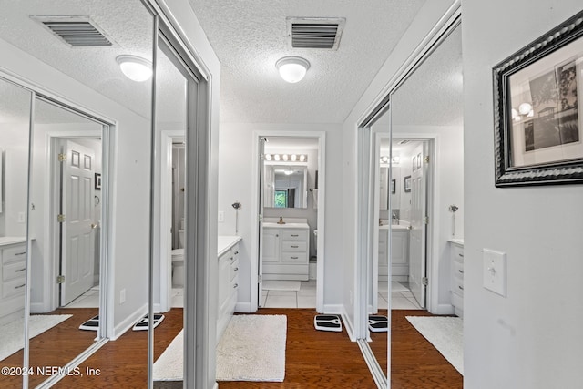 hallway featuring sink, dark wood-type flooring, and a textured ceiling