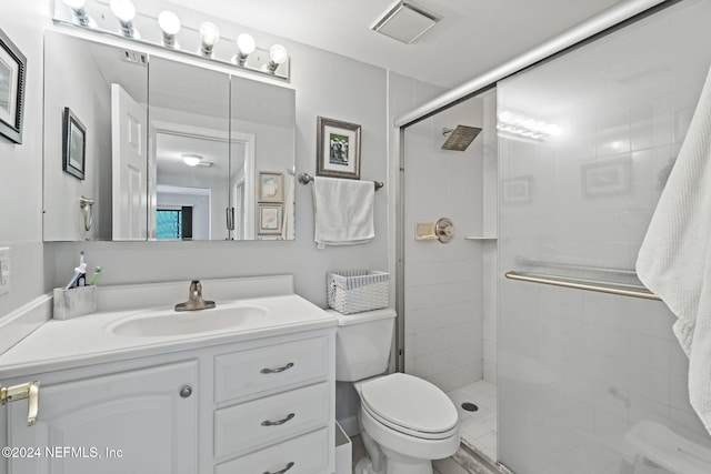 bathroom featuring vanity, a shower with shower door, and toilet