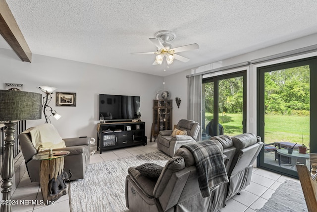 living room with ceiling fan, light tile patterned flooring, and a textured ceiling