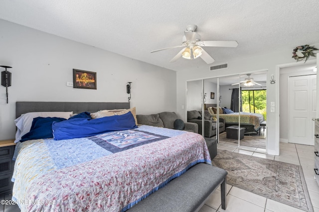 bedroom with light tile patterned floors, a textured ceiling, a closet, and ceiling fan