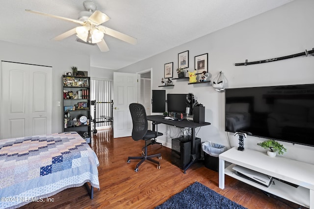 bedroom with hardwood / wood-style flooring, ceiling fan, a textured ceiling, and a closet