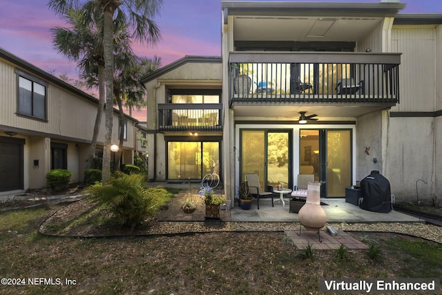 back house at dusk featuring ceiling fan, a patio area, and a balcony