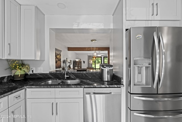 kitchen featuring white cabinets, stainless steel appliances, dark stone counters, and sink