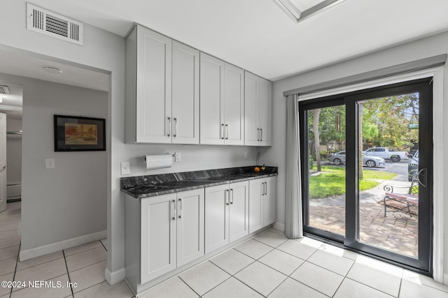 kitchen with dark stone countertops, white cabinets, and light tile patterned floors