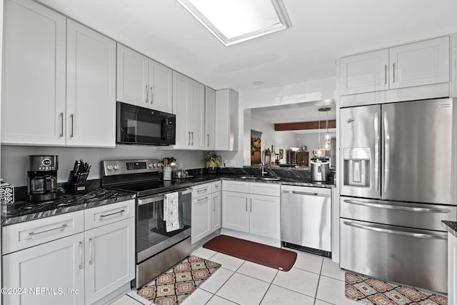 kitchen featuring white cabinetry, sink, stainless steel appliances, dark stone countertops, and light tile patterned floors