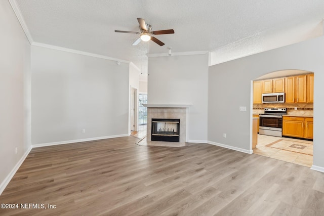 unfurnished living room with a textured ceiling, light hardwood / wood-style floors, ceiling fan, and a tiled fireplace