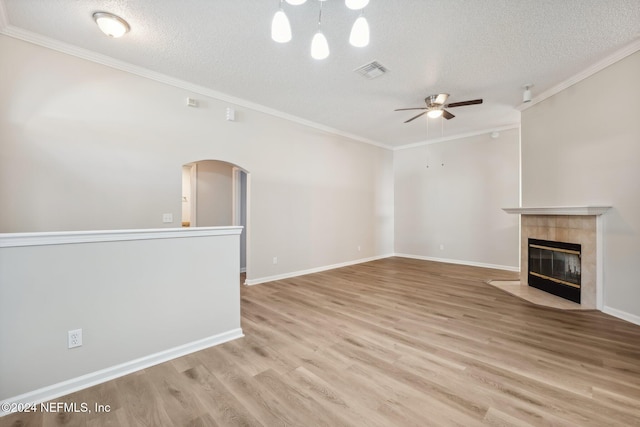 unfurnished living room featuring ceiling fan, light wood-type flooring, a textured ceiling, and a tile fireplace