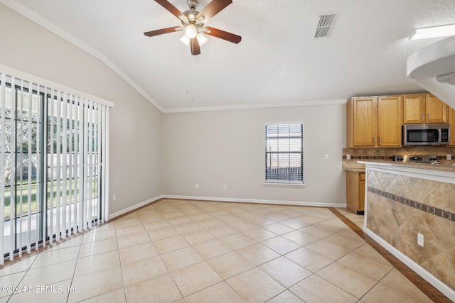 kitchen with a textured ceiling, ceiling fan, crown molding, light tile patterned floors, and lofted ceiling