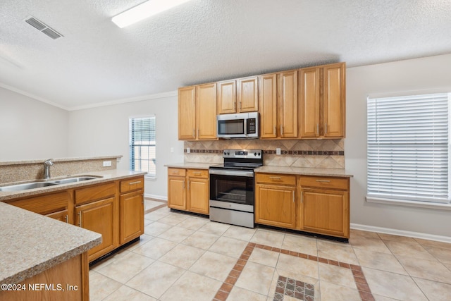 kitchen with crown molding, sink, light tile patterned floors, tasteful backsplash, and stainless steel appliances