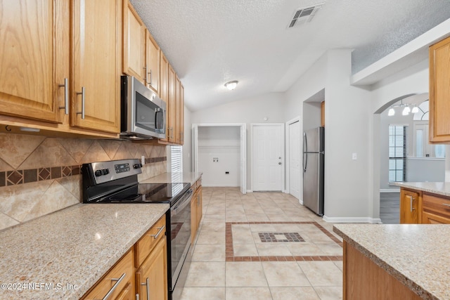 kitchen featuring a textured ceiling, ceiling fan, stainless steel appliances, and vaulted ceiling