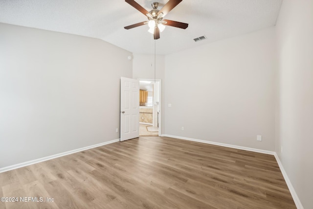 spare room featuring a textured ceiling, wood-type flooring, and lofted ceiling