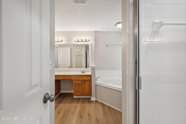 bathroom with hardwood / wood-style flooring, vanity, a textured ceiling, and independent shower and bath