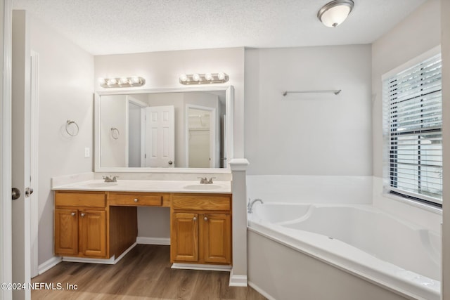 bathroom featuring hardwood / wood-style floors, a washtub, a textured ceiling, and vanity