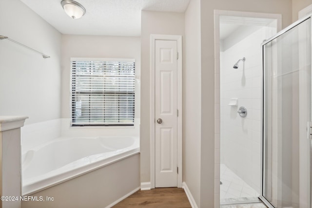 bathroom featuring wood-type flooring, a textured ceiling, and plus walk in shower