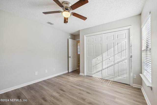 unfurnished bedroom featuring ceiling fan, a closet, a textured ceiling, and light hardwood / wood-style flooring