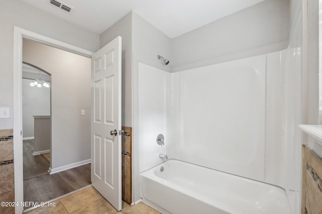 bathroom featuring tile patterned floors, a notable chandelier, and bathtub / shower combination