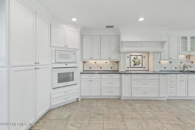 kitchen with backsplash, white cabinets, and white appliances