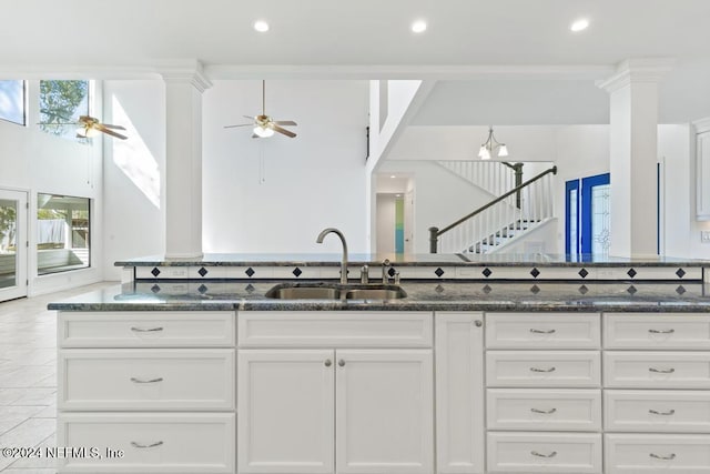 kitchen with white cabinetry, sink, ceiling fan, dark stone counters, and light tile patterned flooring