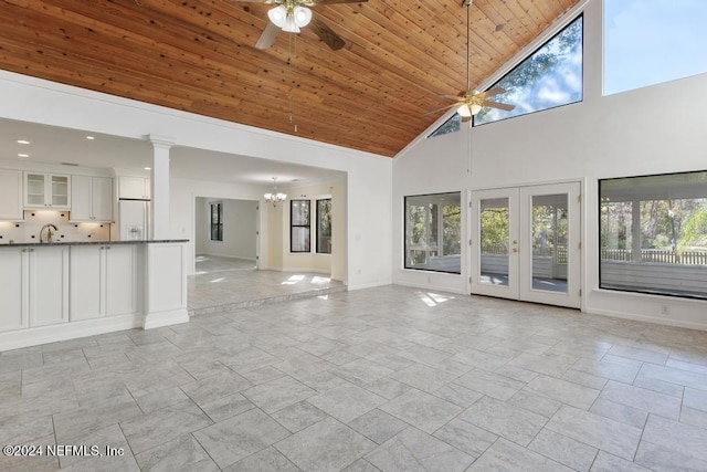 unfurnished living room featuring high vaulted ceiling, french doors, ceiling fan with notable chandelier, sink, and wood ceiling